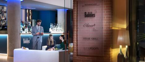 A modern lounge bar with a bar area, seating, and a wine room sign.