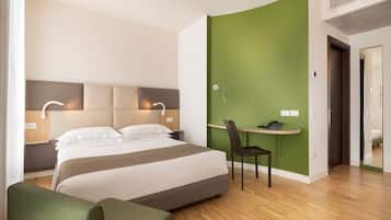 Quarto de hotel moderno com uma cama grande, uma escrivaninha e uma parede verde de destaque.
