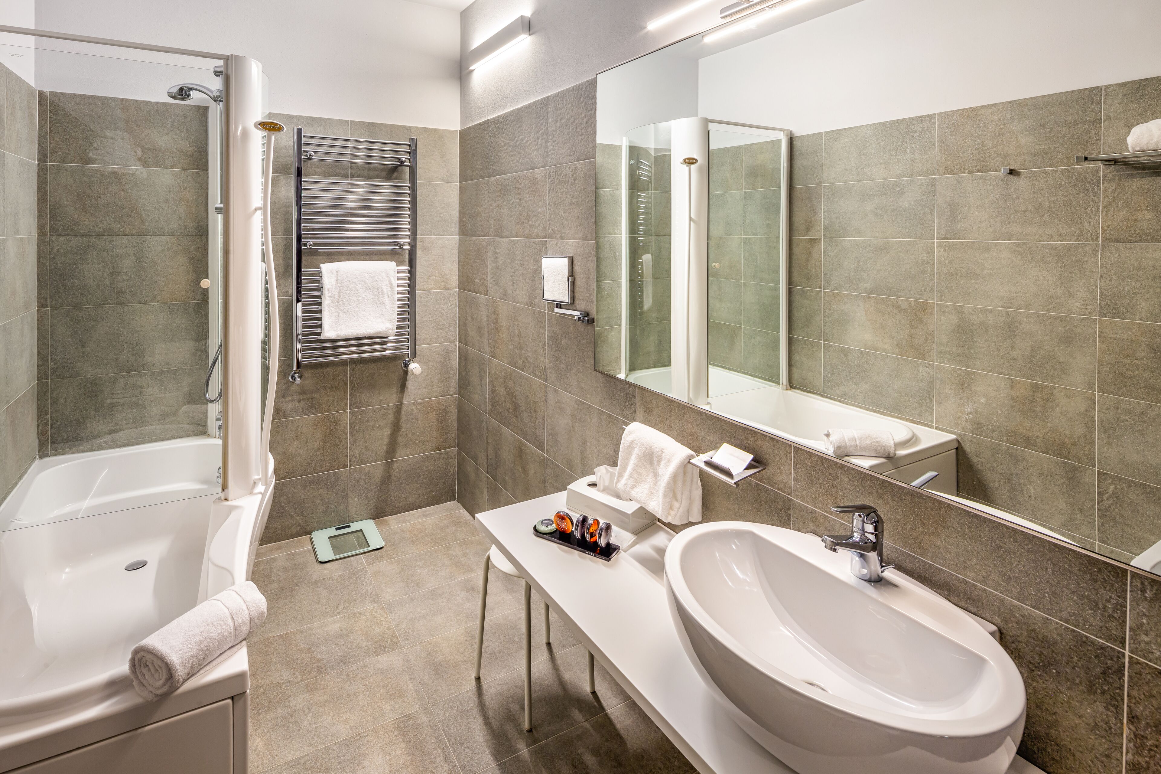 Une salle de bain moderne avec une baignoire, un grand lavabo et un miroir.