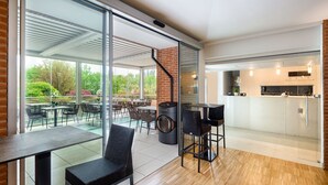 Een moderne keuken met een ingebouwde oven en een eethoek met glazen wand met uitzicht op een tuin.