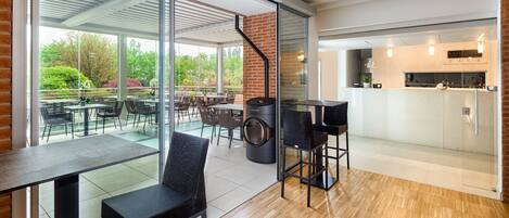 A modern kitchen with a built-in oven and a dining area with a glass wall overlooking a garden.