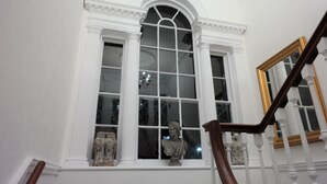 A grand staircase with white columns and a large arched window. - White Linen Whitby, Room Only (Whitby)