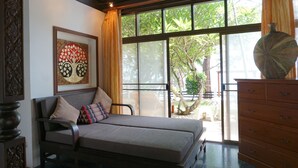 Una habitación con una cama, un aparador de madera, un ventanal grande y una obra de arte enmarcada en la pared.