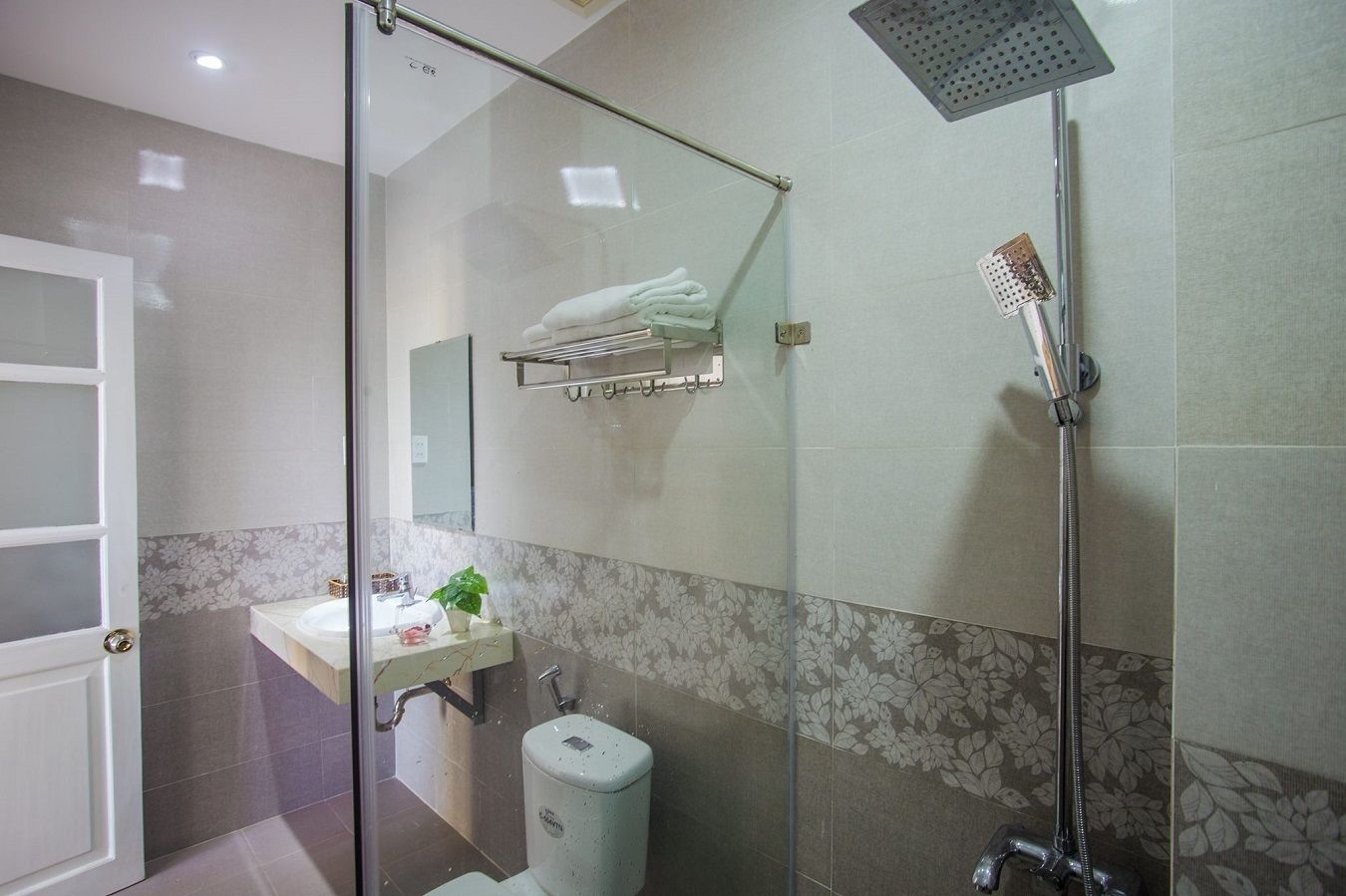 Um banheiro moderno com box de vidro, pia com bancada de mármore e vaso sanitário.