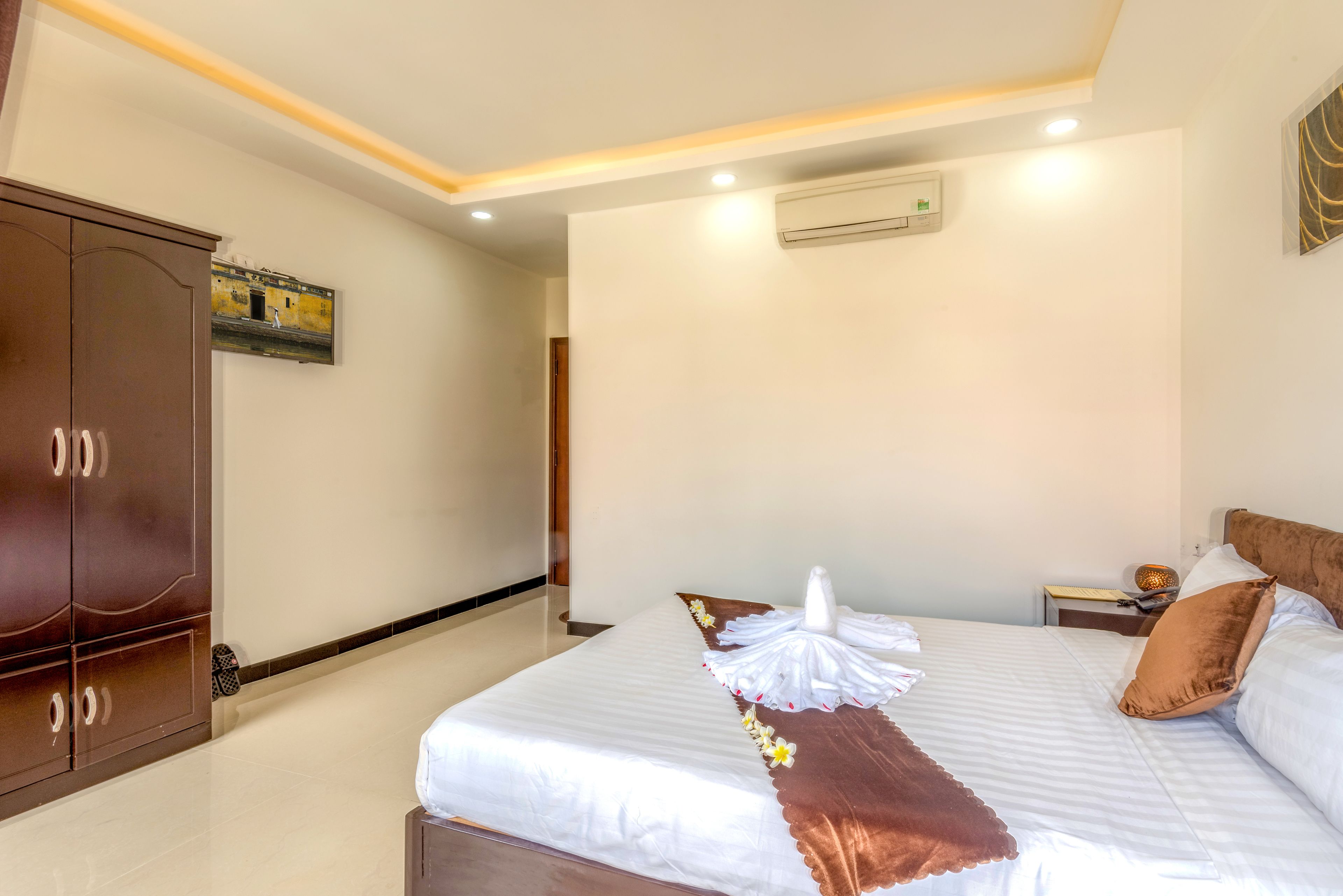 Una habitación de hotel con cama, armario, equipo de aire acondicionado y mesita de noche.