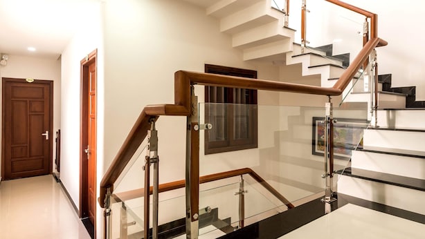 A modern staircase with glass railings and wooden handrails, leading to an upper floor. - Miss Ten Homestay (Da Nang)