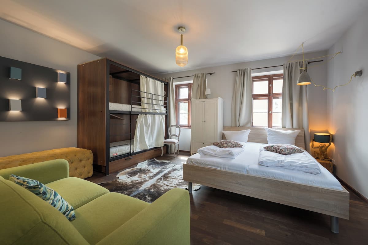 Ein modernes Hotelzimmer mit Etagenbett, einer Couch, einem Schreibtisch und einer Lampe.