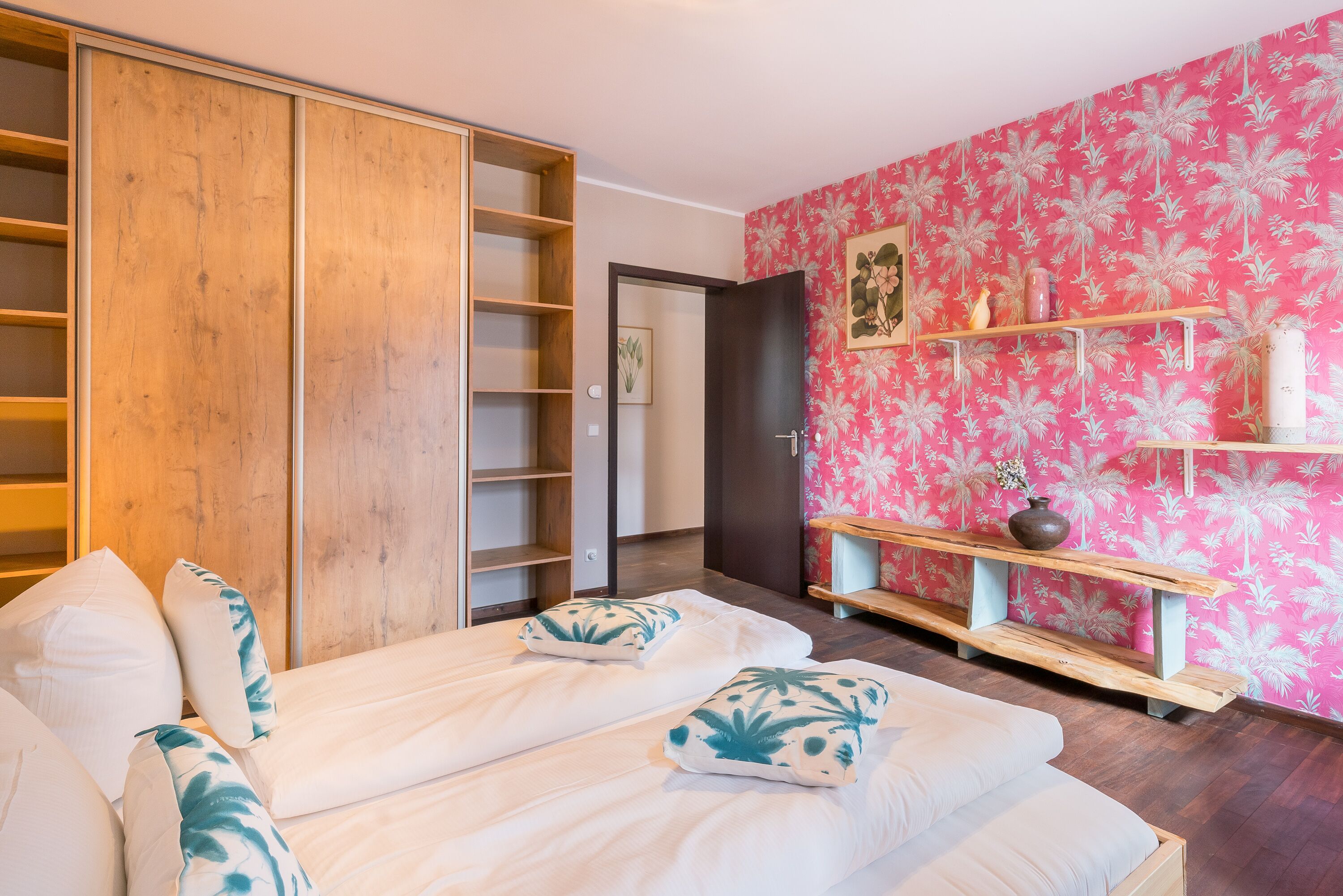 A bedroom with a bed, a wardrobe, and a pink floral wall.