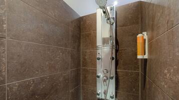 Una ducha con cabezal de ducha de mano y panel de control en la pared.