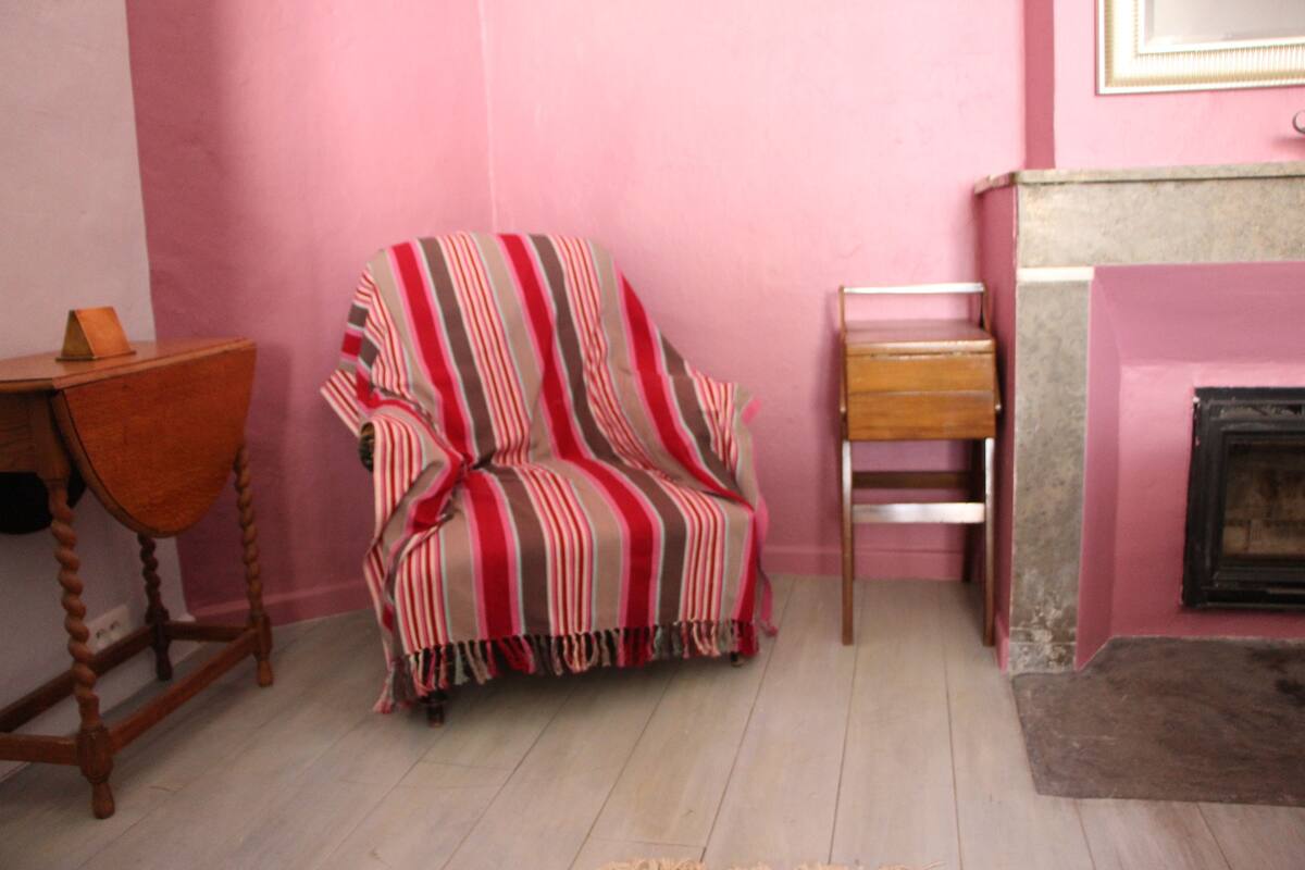 Una habitación con un sillón a rayas, una mesita de madera y una chimenea.