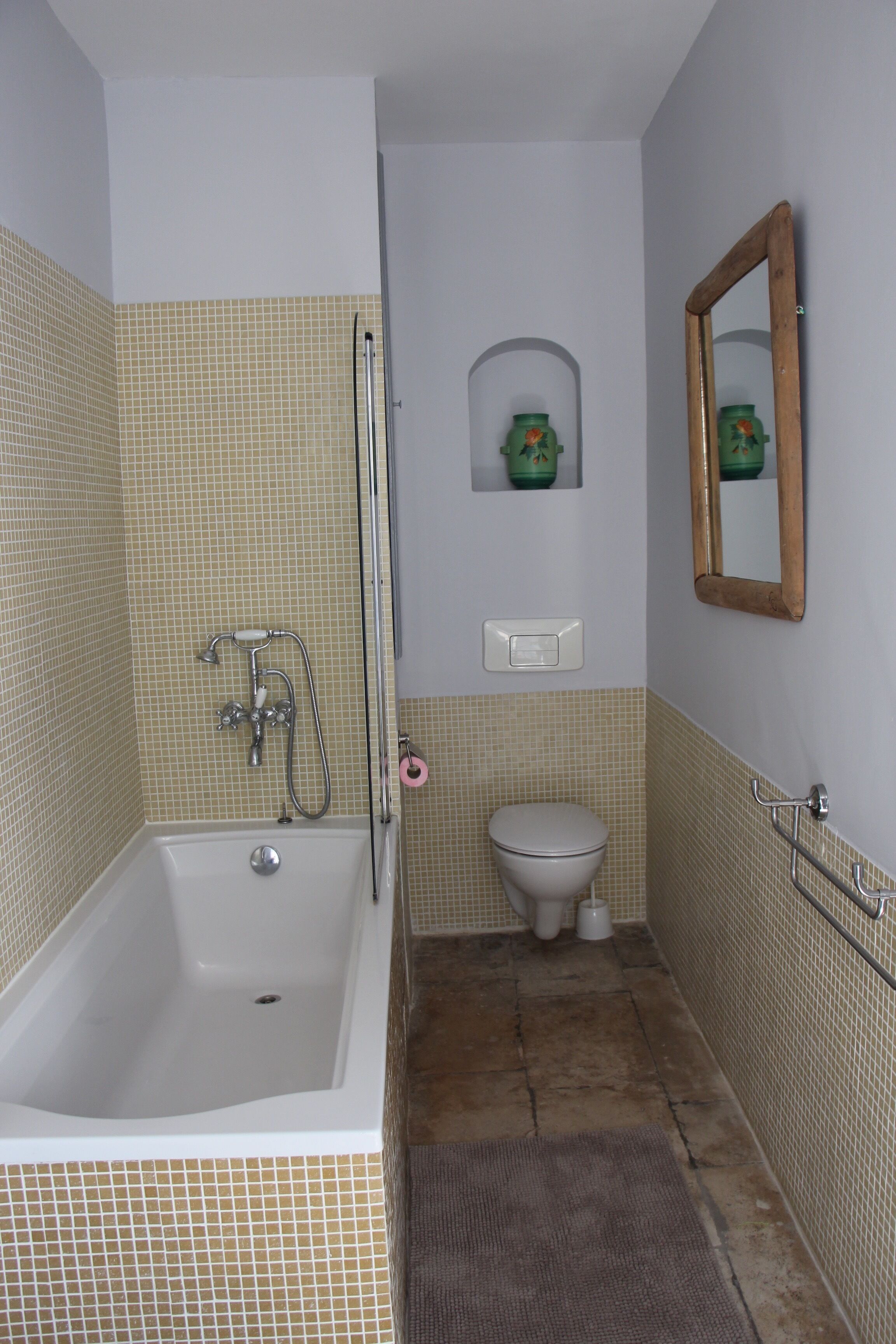 Une salle de bain avec une baignoire, des toilettes et un miroir.
