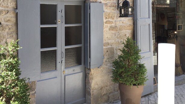 A stone building with a metal plaque, a window with shutters, and a door. - Maison Anila (Barjac)