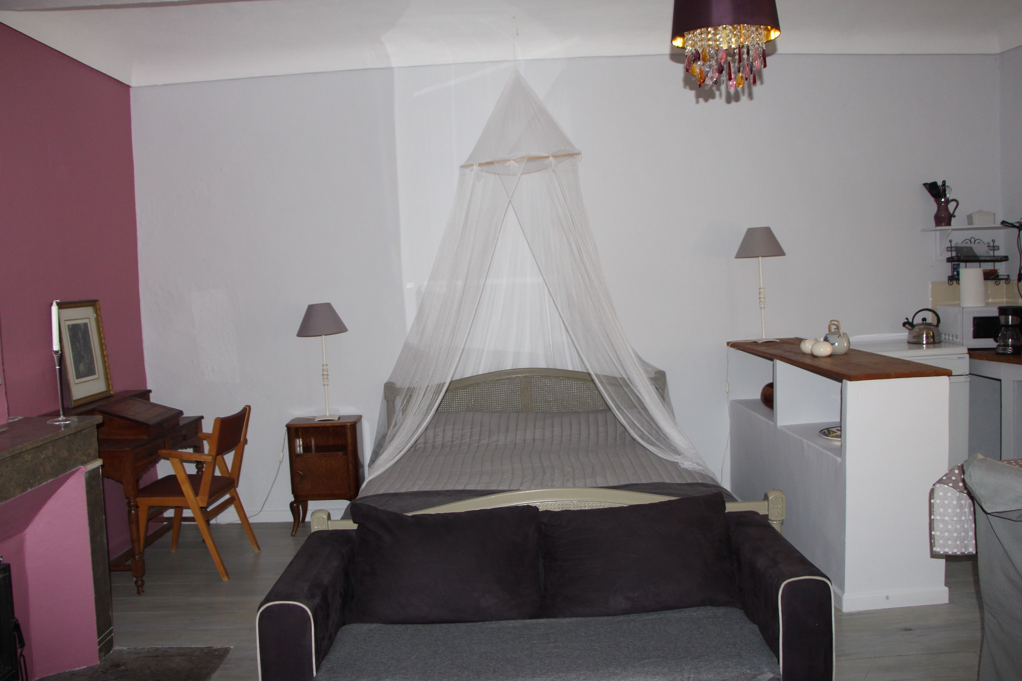 Een slaapkamer met een bed, nachtkastjes, een bureau en een stoel.