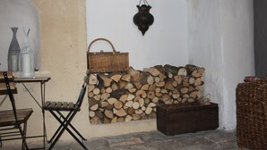 A rustic interior with a stone wall, a wicker basket, a wooden bench, and a woven chair. - Maison Anila (Barjac)