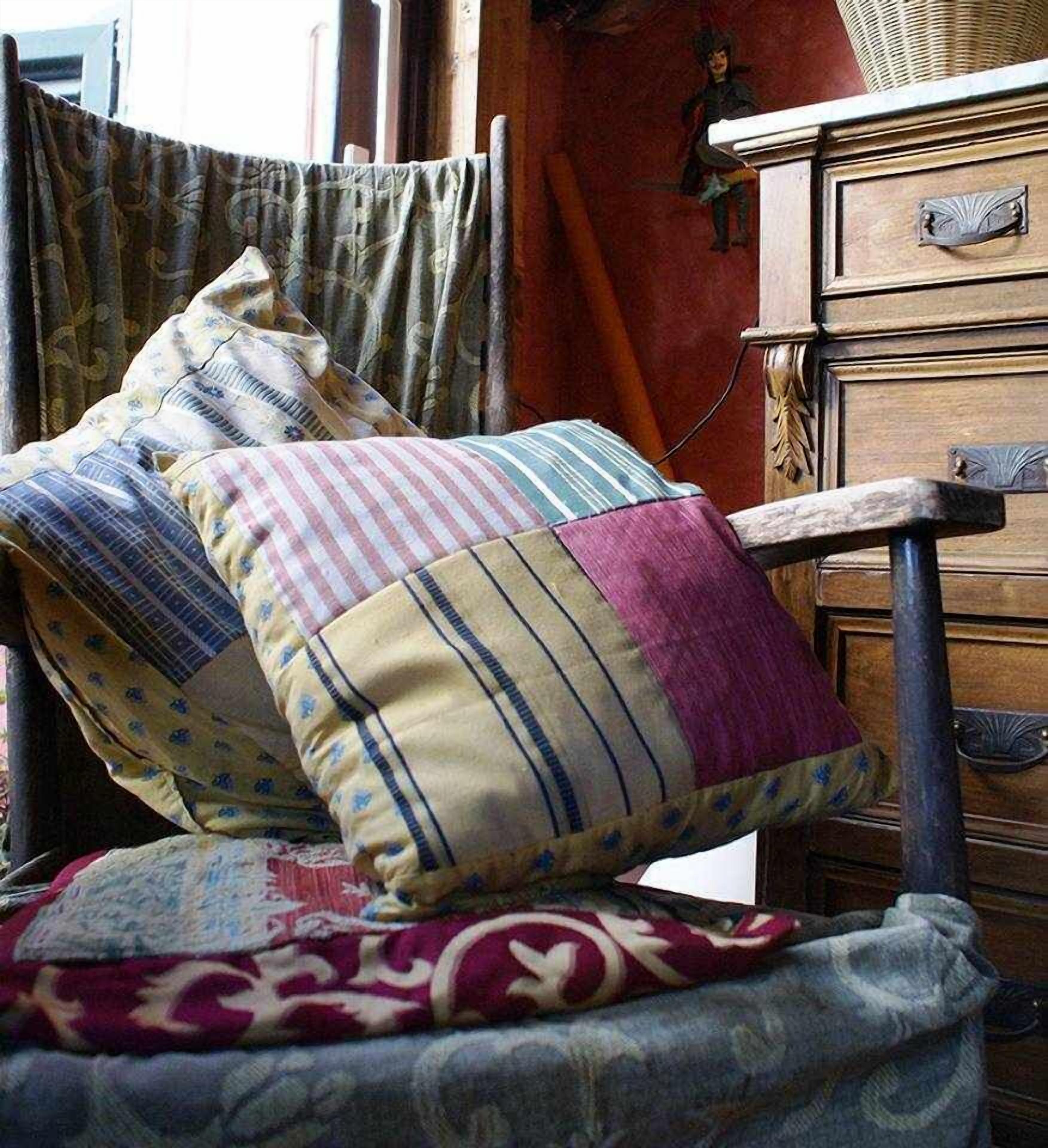 A bed with multiple pillows and a patterned blanket.