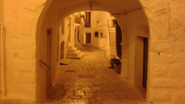 An arched corridor with stone flooring, leading to a building entrance. - Arco Michele (Putignano)