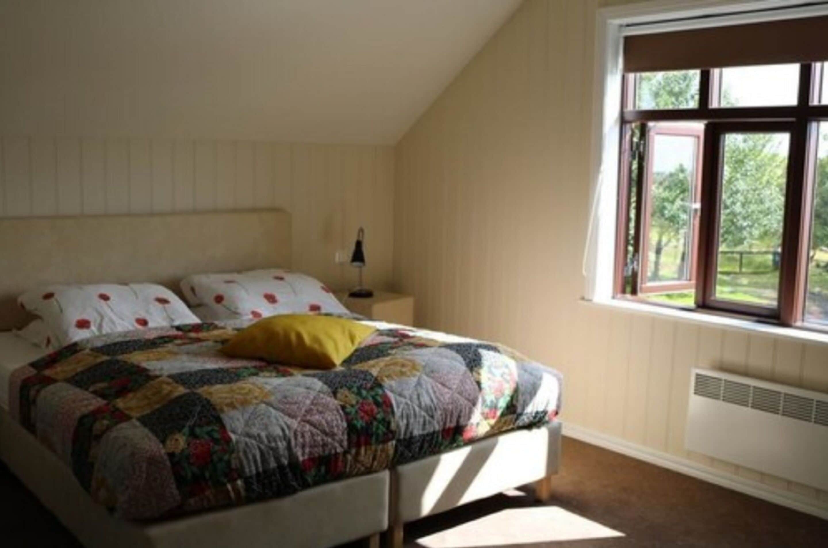 Une chambre à coucher avec un lit, une table de chevet, une fenêtre et un radiateur.
