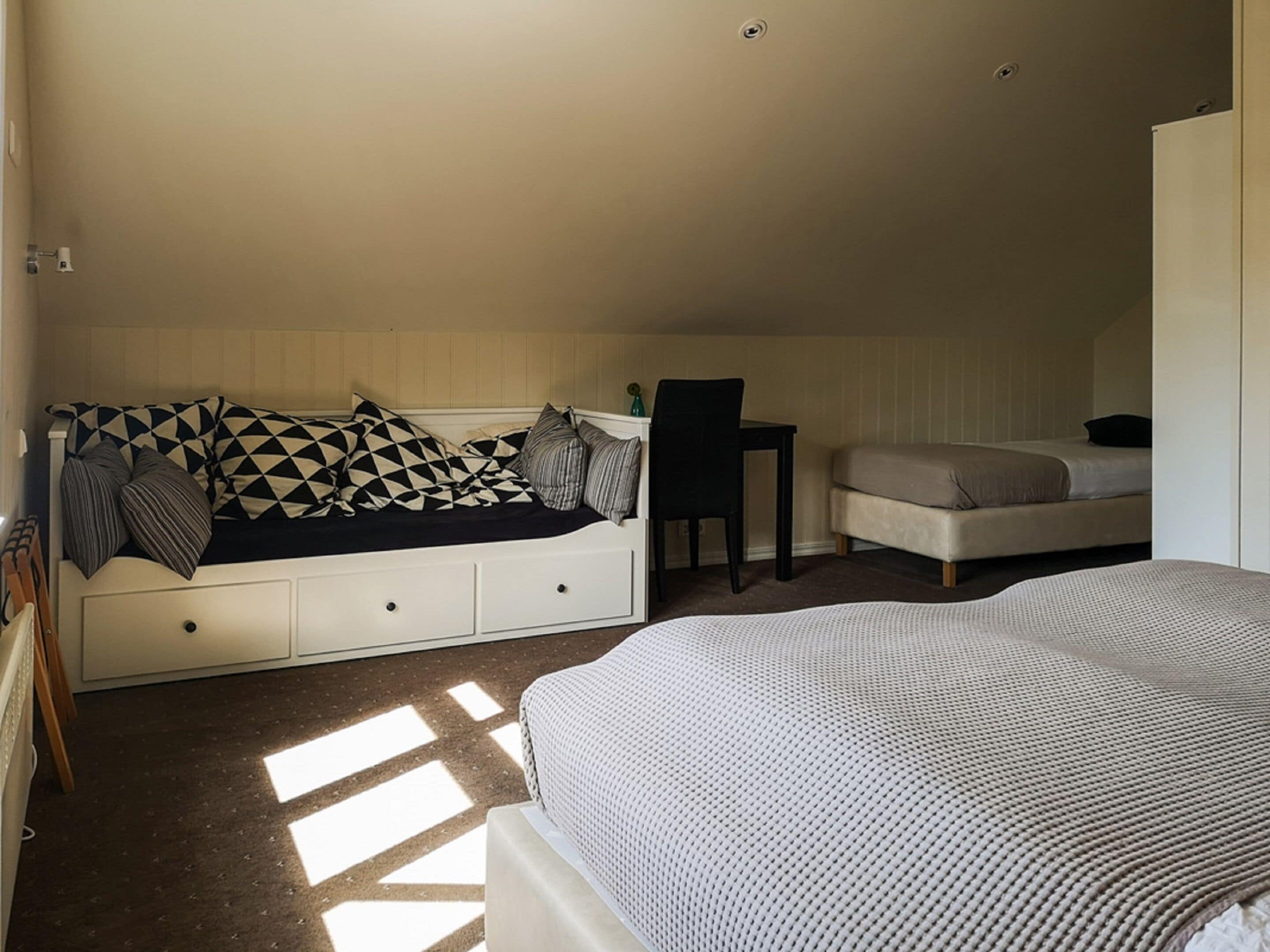 A bedroom with a bed, a sofa bed, a chair, and a desk.