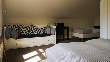 A bedroom with a bed, a sofa bed, a chair, and a desk.