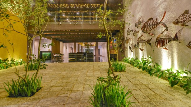 A spacious indoor area with a tiled floor, green plants, and a wall decorated with fish sculptures. - Golden Pearl Tangalle Beach (Tangalle)