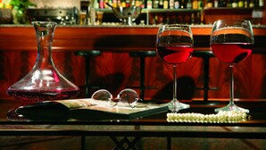 Um bar com garrafas, copos e balcão.