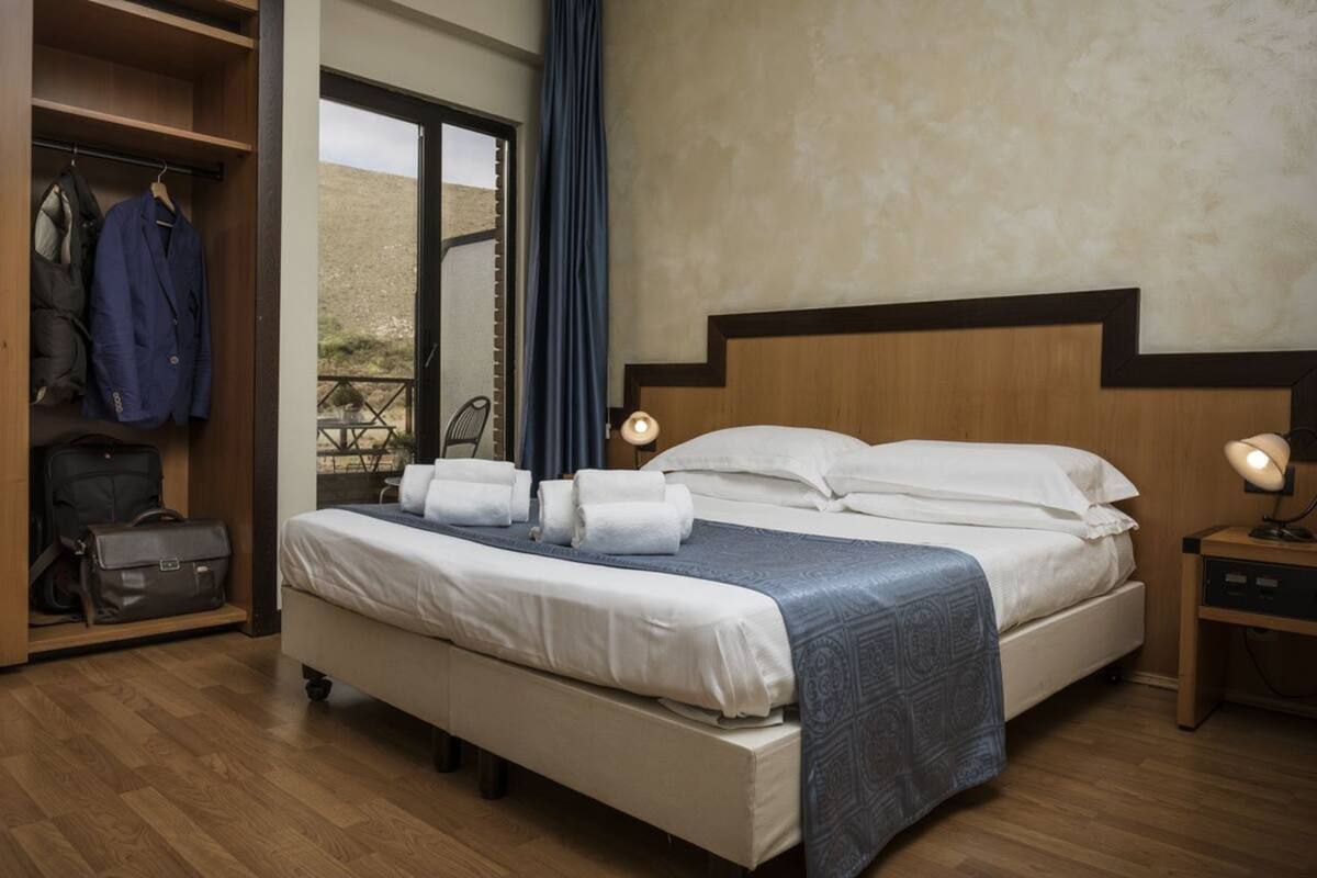 A hotel room with a bed, a wardrobe, a desk, and a chair.
