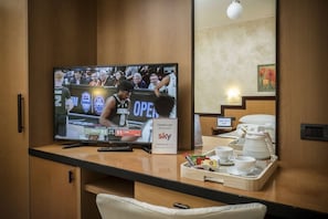 A hotel room with a television displaying a basketball game, a tray with cups and a teapot, and a sign indicating Sky channel availability. - Hotel Olimpia (Scurcola Marsicana)