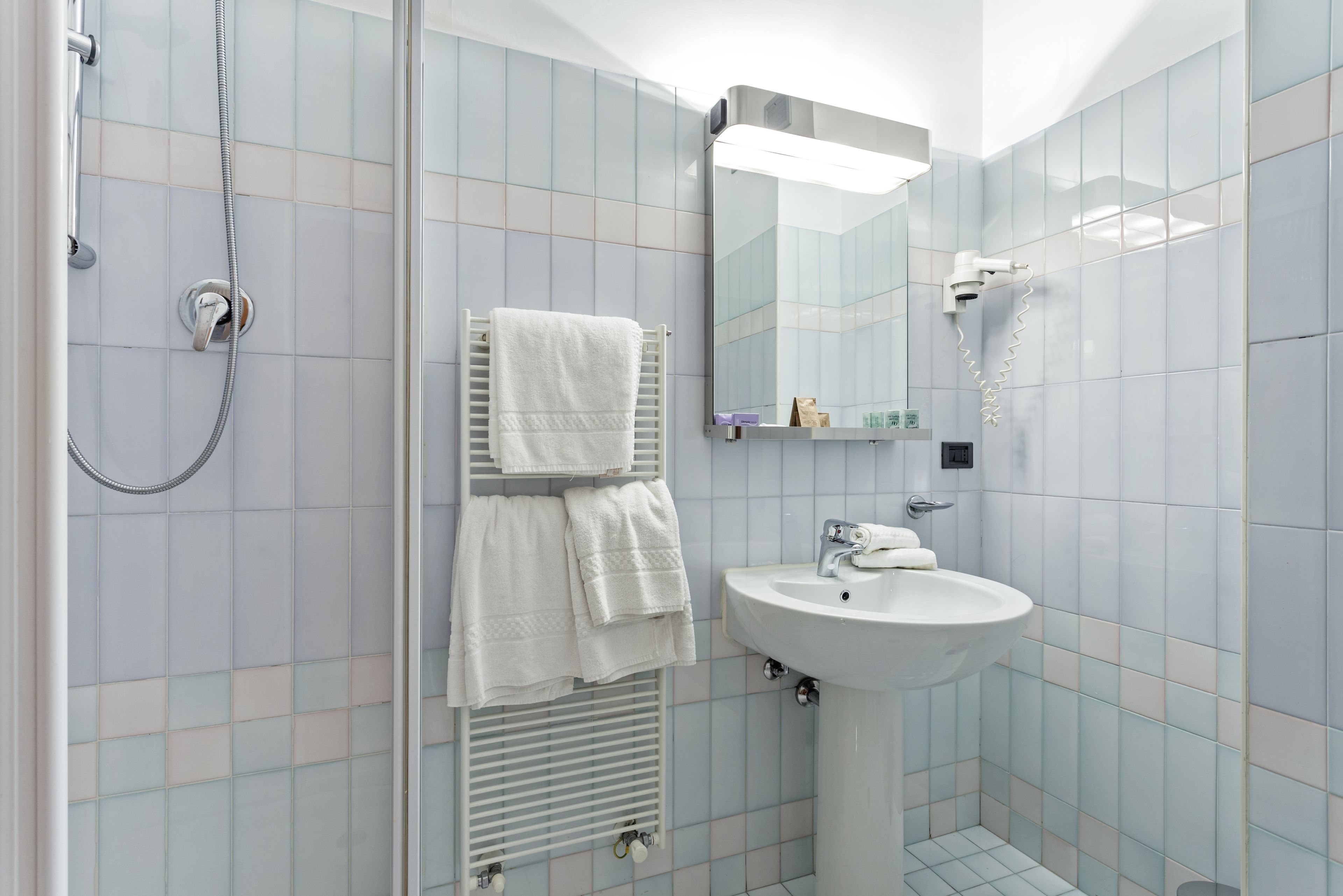 A bathroom with a shower, sink, and towel rack.