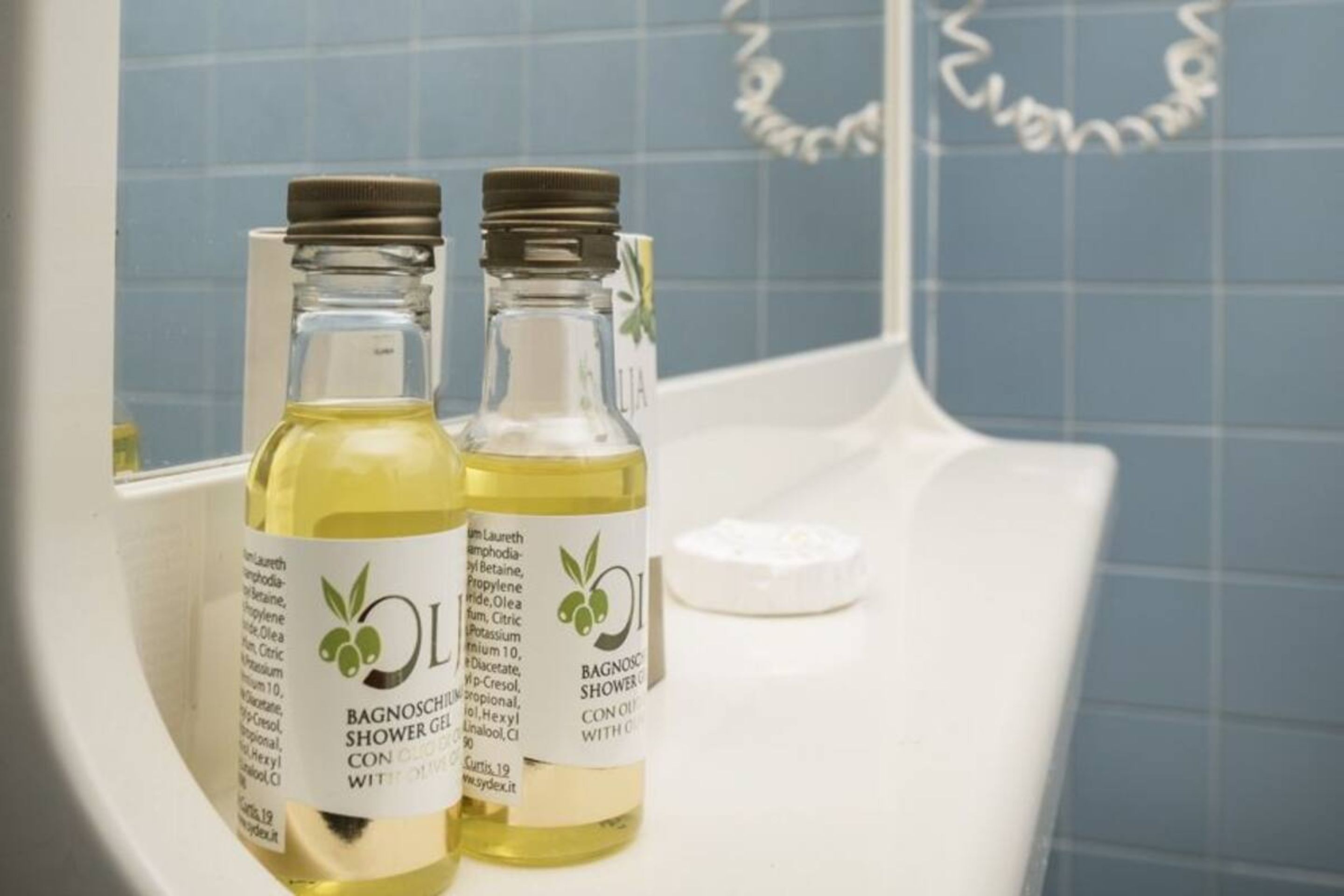 Deux flacons de gel douche Bagnocchi à l’huile de Con, posés sur le comptoir d’une salle de bain.