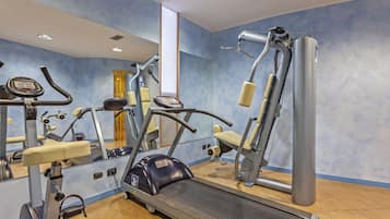 Un gimnasio con máquinas de cardio, un espejo y una ventana con cortinas.