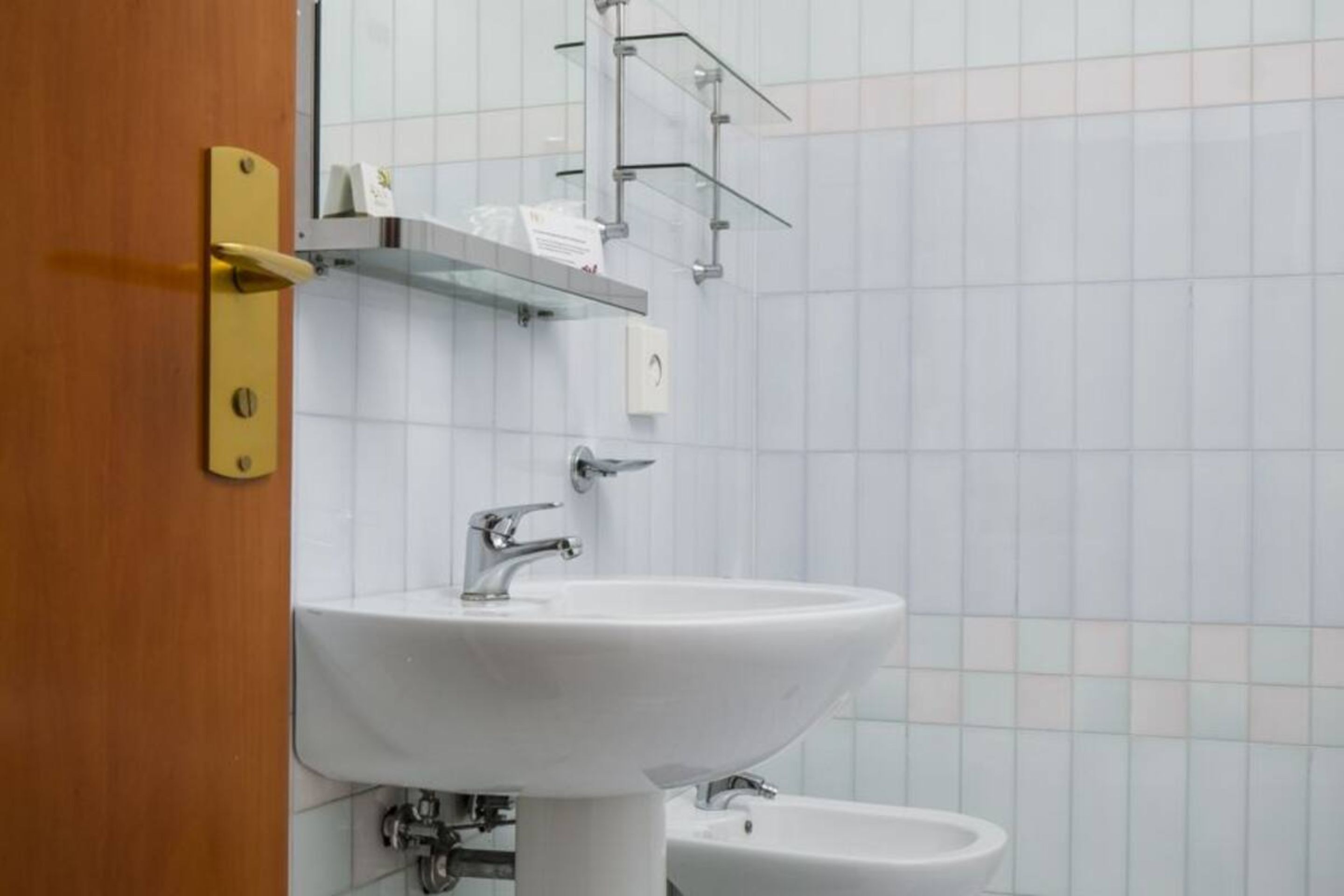 A bathroom with a white sink, a bidet, and a wooden door.