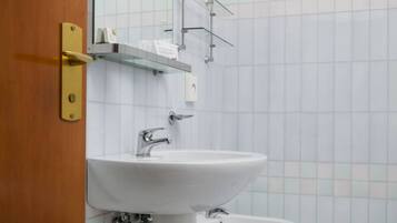 A bathroom with a white sink, a bidet, and a wooden door.