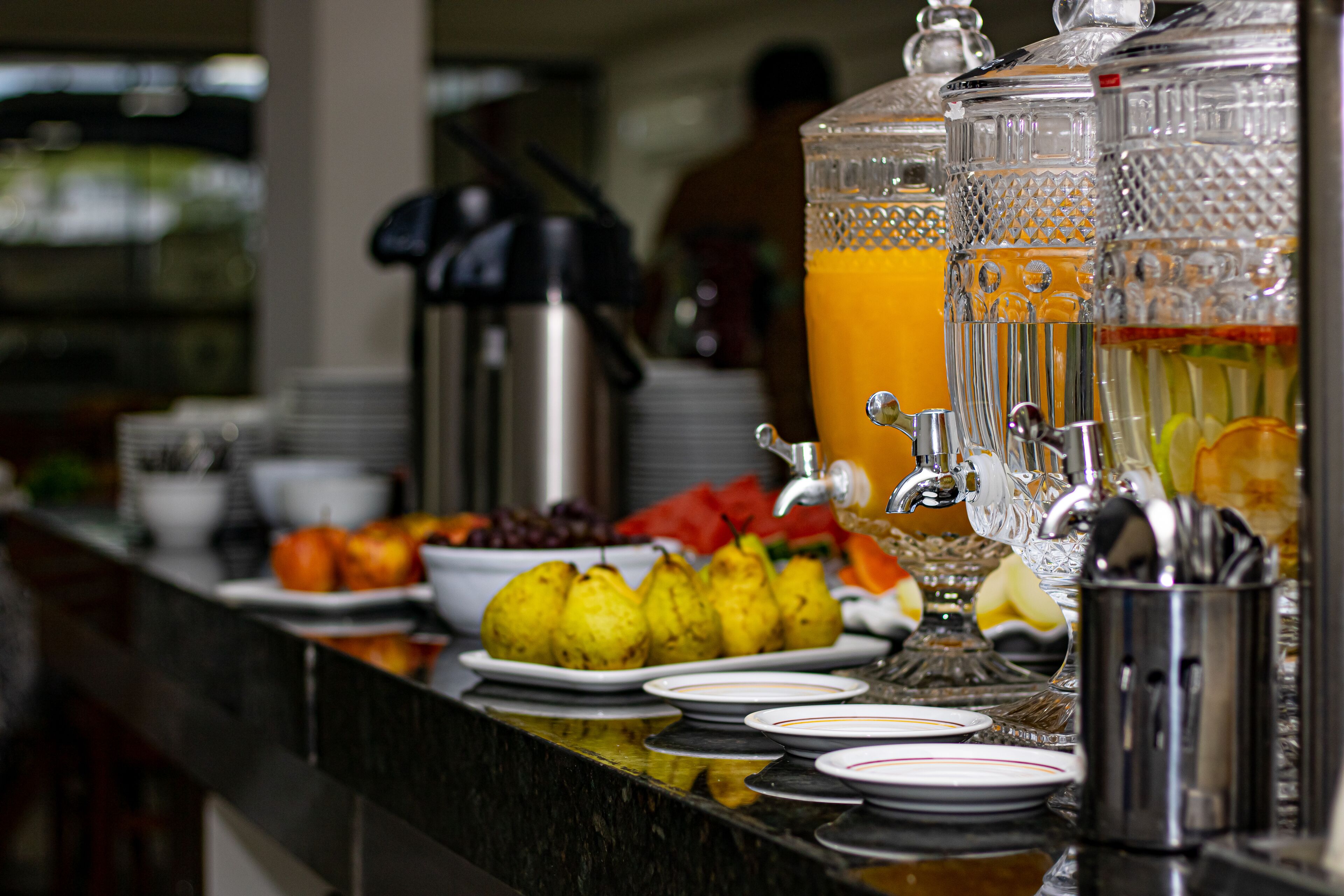 Een buffet met verschillende soorten fruit, een koffiezetapparaat en een fruitsapautomaat.