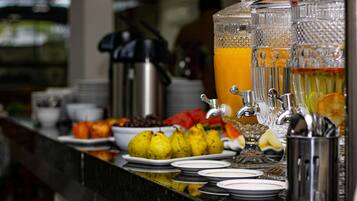 Een buffet met verschillende soorten fruit, een koffiezetapparaat en een fruitsapautomaat.