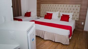 A hotel room with two beds, a wooden headboard, and a white refrigerator.