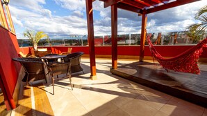 Una terraza con mobiliario de mimbre, una hamaca y vistas a la ciudad.