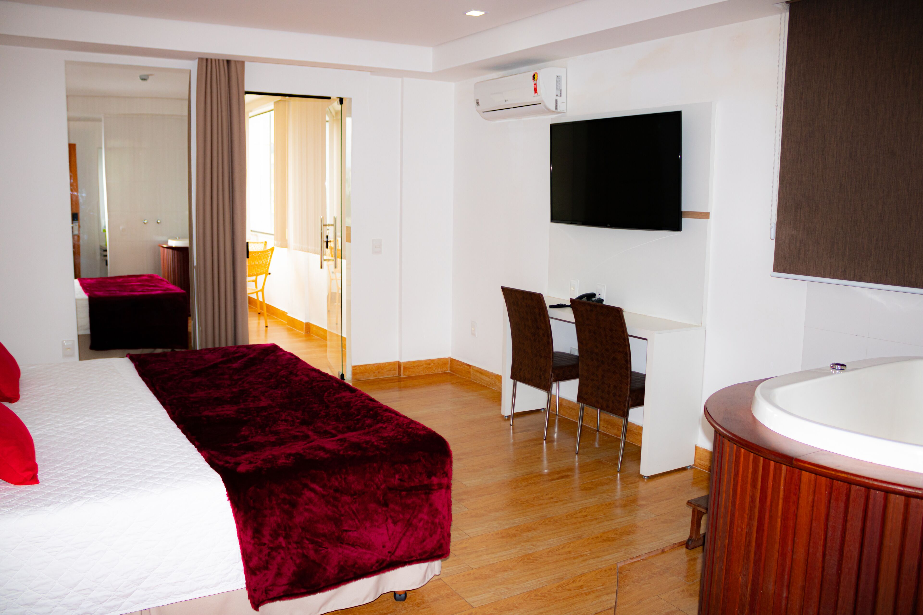 Una habitación de hotel con una cama, un escritorio con dos sillas, un televisor y una bañera.