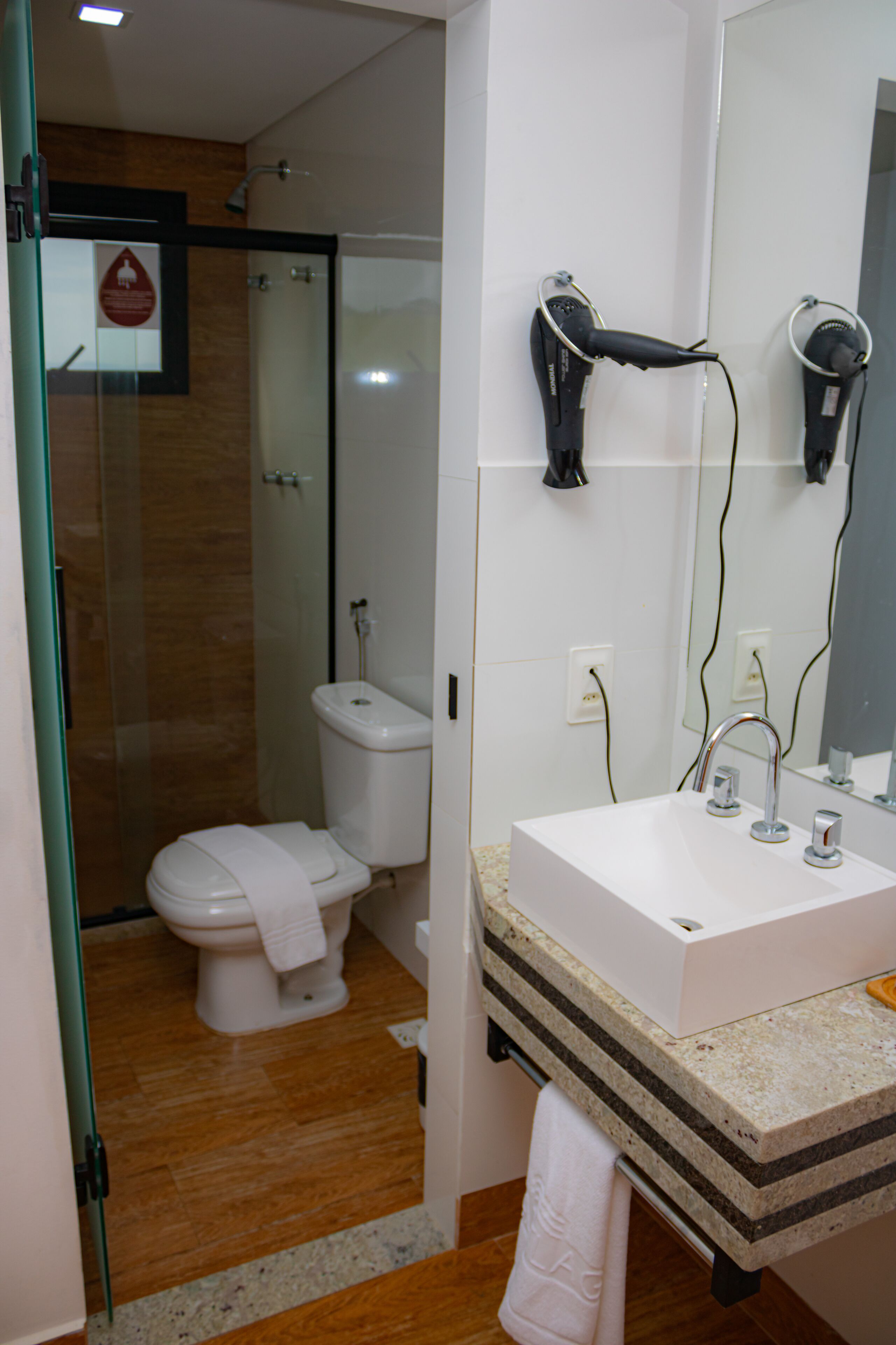 Un baño con lavamanos blanco, cabina de ducha de vidrio y un inodoro.