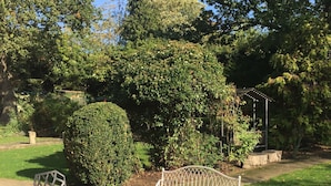 An outdoor patio with a round table and metal chairs, surrounded by gravel and greenery. - Edgware Bed and Breakfast (Edgware)