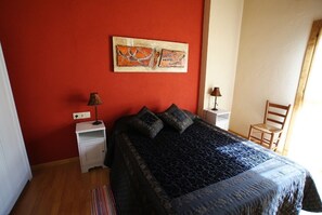 A bedroom with a bed, two bedside tables, a chair, and a painting on the wall. - Mas Prat (La Vall de Bianya)