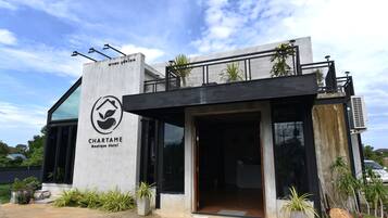 Un hotel boutique moderno con fachada de hormigón, amplia entrada de vidrio y plantas exteriores.