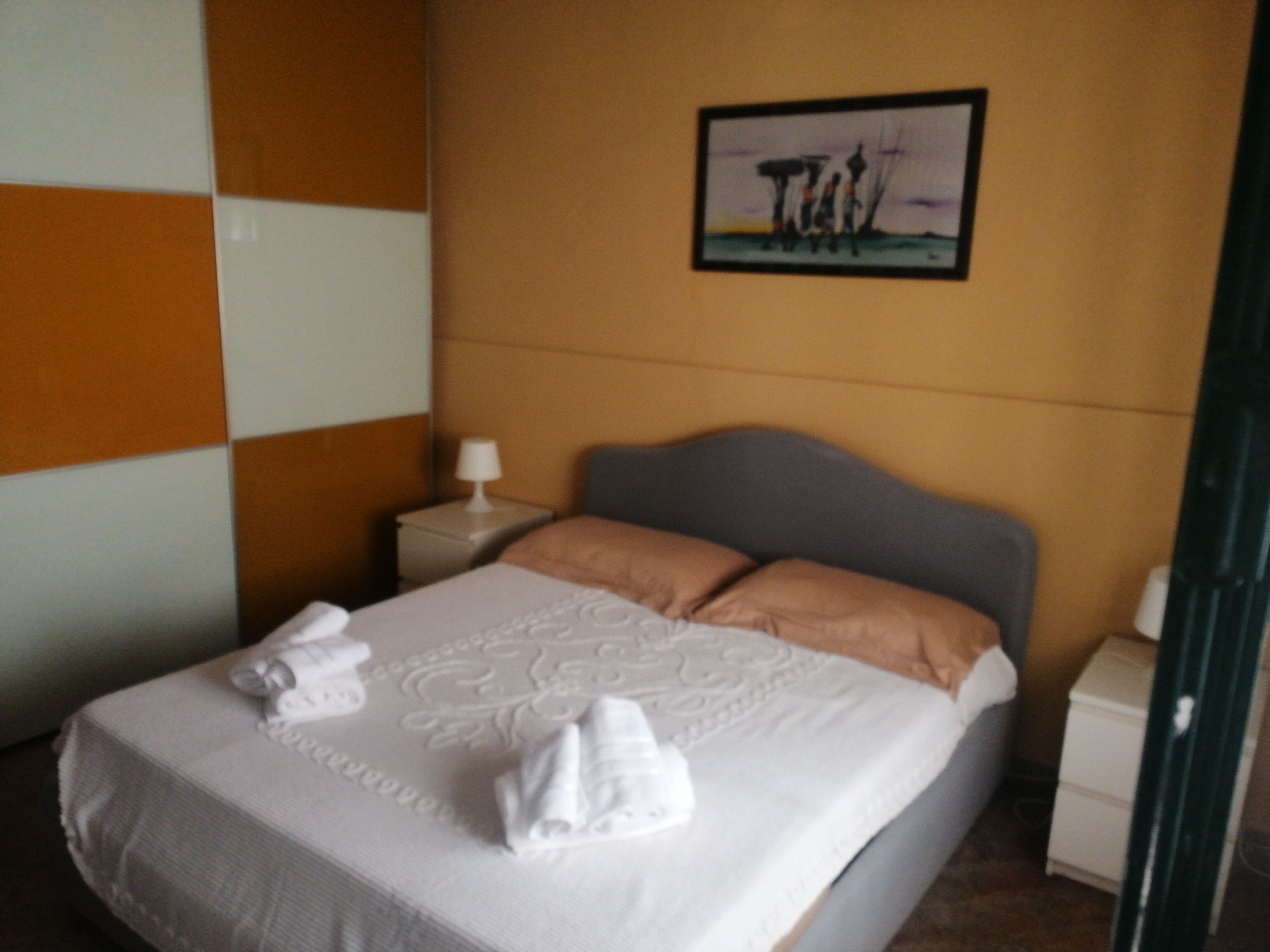 Une chambre d’hôtel avec un lit, une table de chevet, une lampe et un tableau au mur.