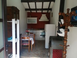 A compact kitchen with a dining area, a wooden cabinet, and a table with a vase. - La Valle Del Poeta (Castelfidardo)