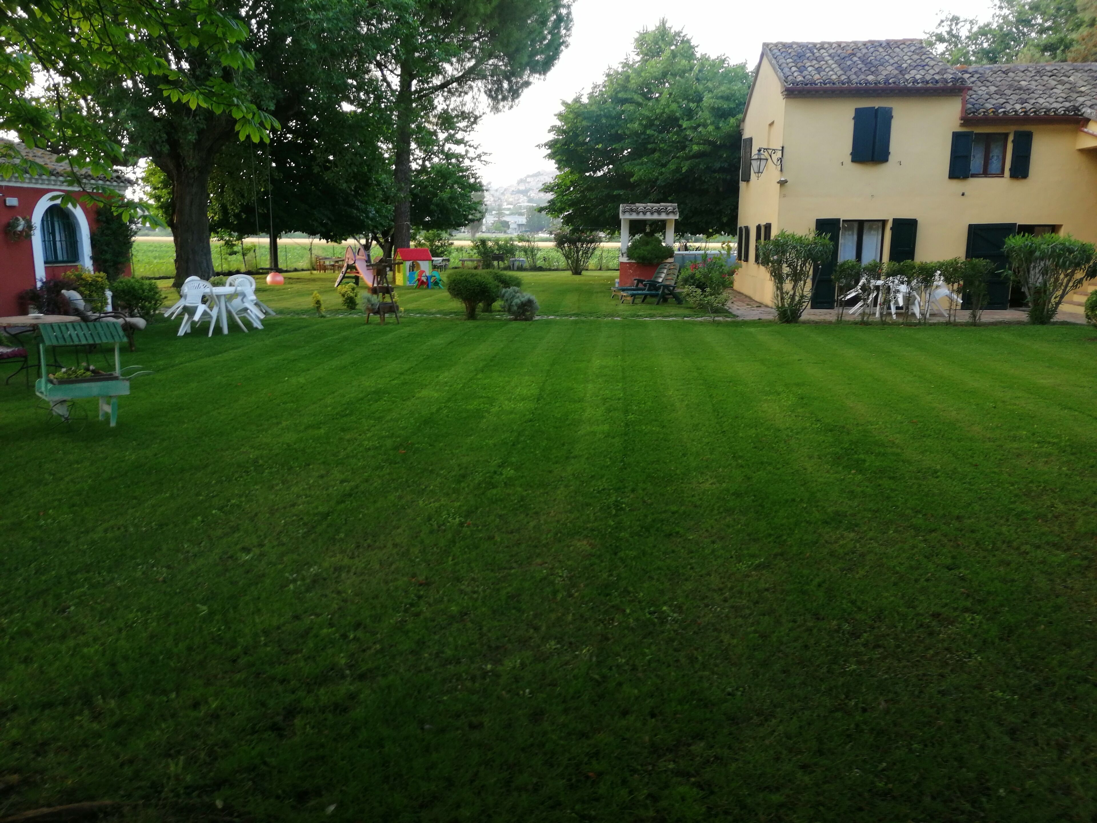 A well-maintained lawn with outdoor seating, a small play area, and a building with a tiled roof.