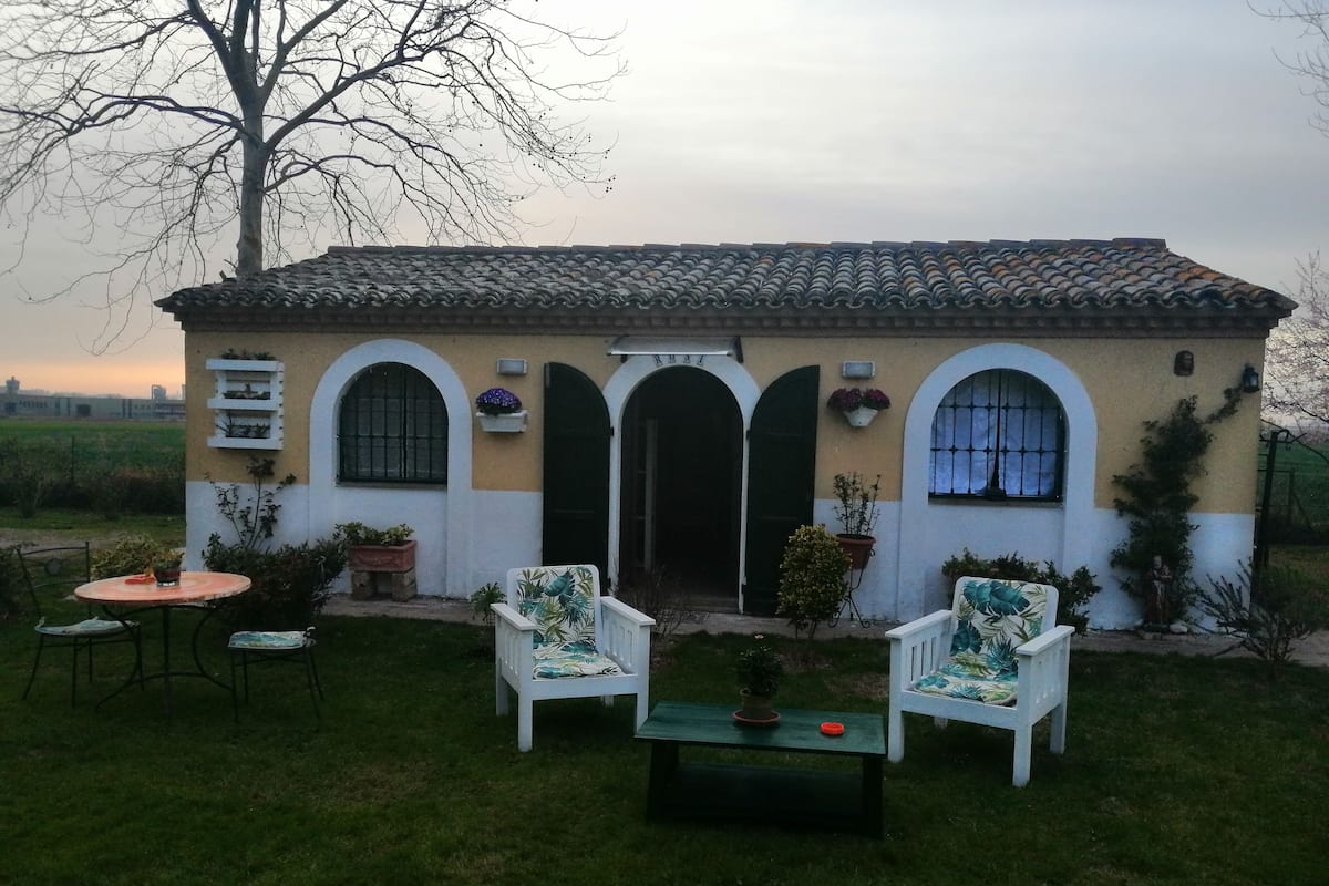 A house with a tiled roof, arched doorways, and a small patio with two chairs and a table.