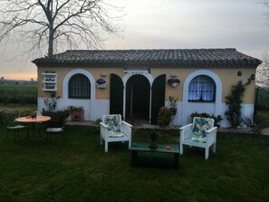 A house with a tiled roof, arched doorways, and a small patio with two chairs and a table. - La Valle Del Poeta (Castelfidardo)