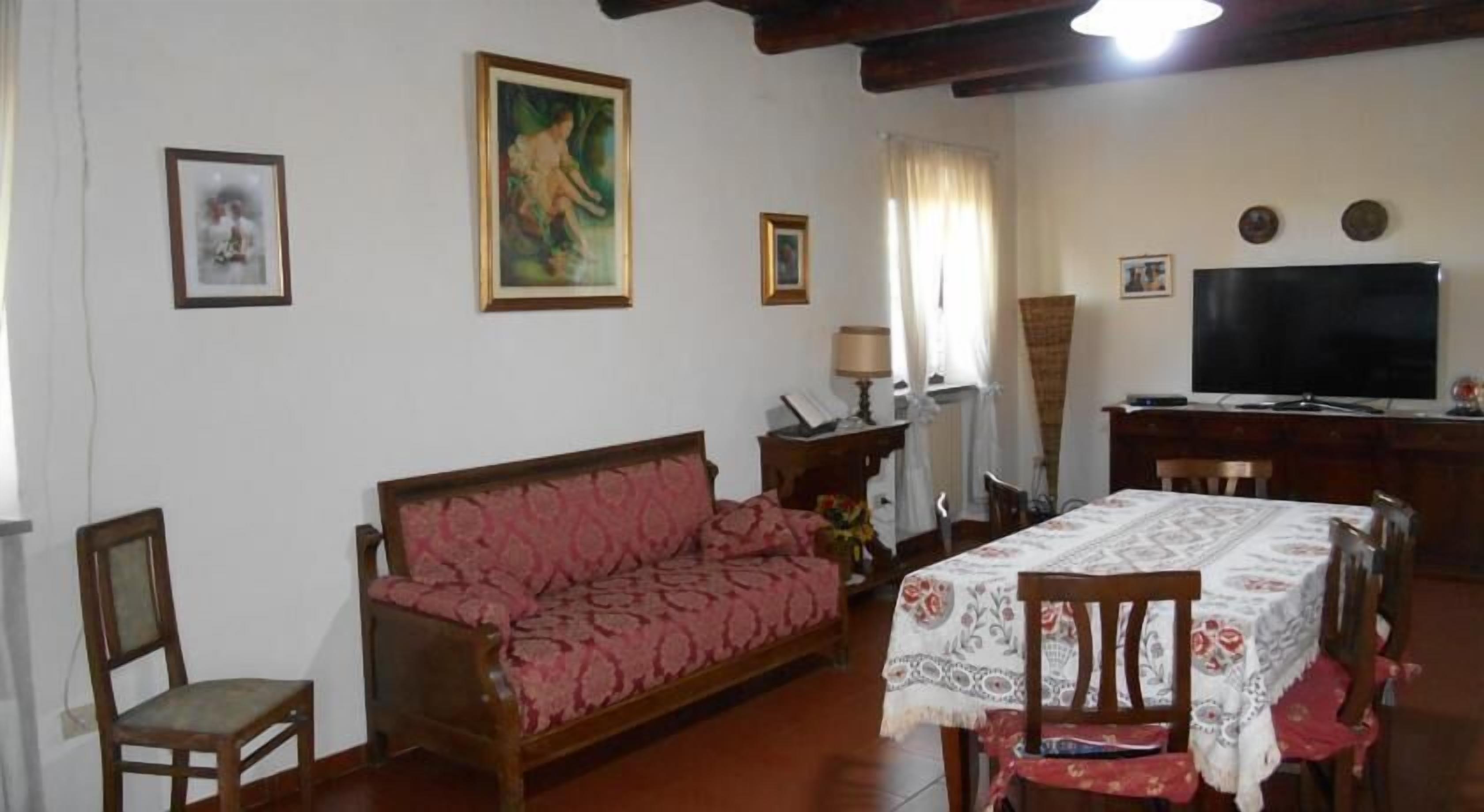 Un salon comprenant un canapé, une table à manger, des chaises, un téléviseur et des tableaux encadrés accrochés aux murs.