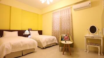 A hotel room with two beds, a small table with a chair, a vanity with a mirror, and an air conditioning unit.