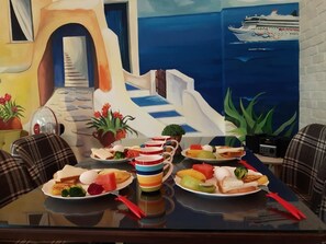 A dining table set with plates of food, a striped mug, and a ship in the background. - Love Boat (Taitung)