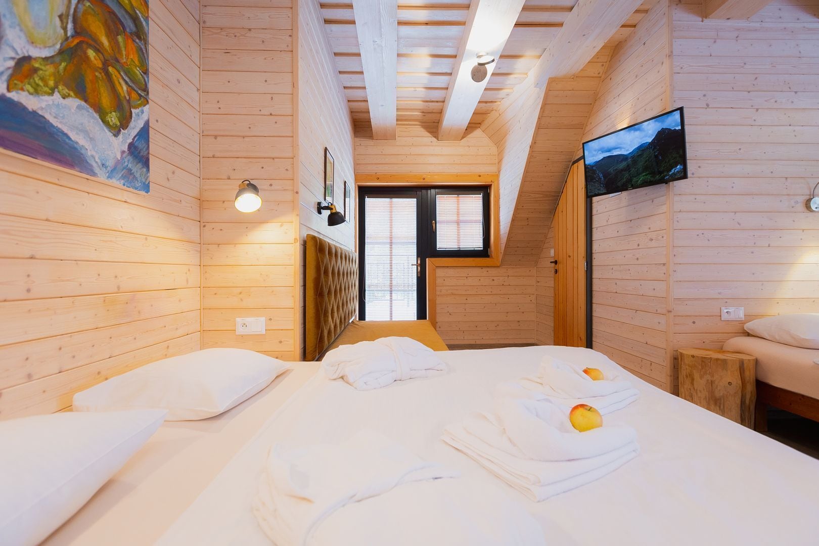 Um quarto de cabana de madeira aconchegante, com uma cama, uma janela e uma televisão na parede.